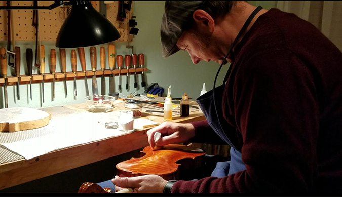 Tumbas works on a violin in his workshop.